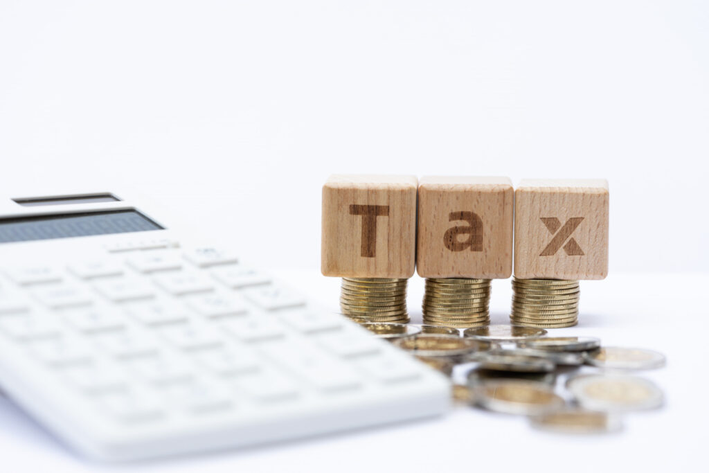 Deduction of Tax on Yearly Interest in the UK , image with coins and blocks with capital letter TAX